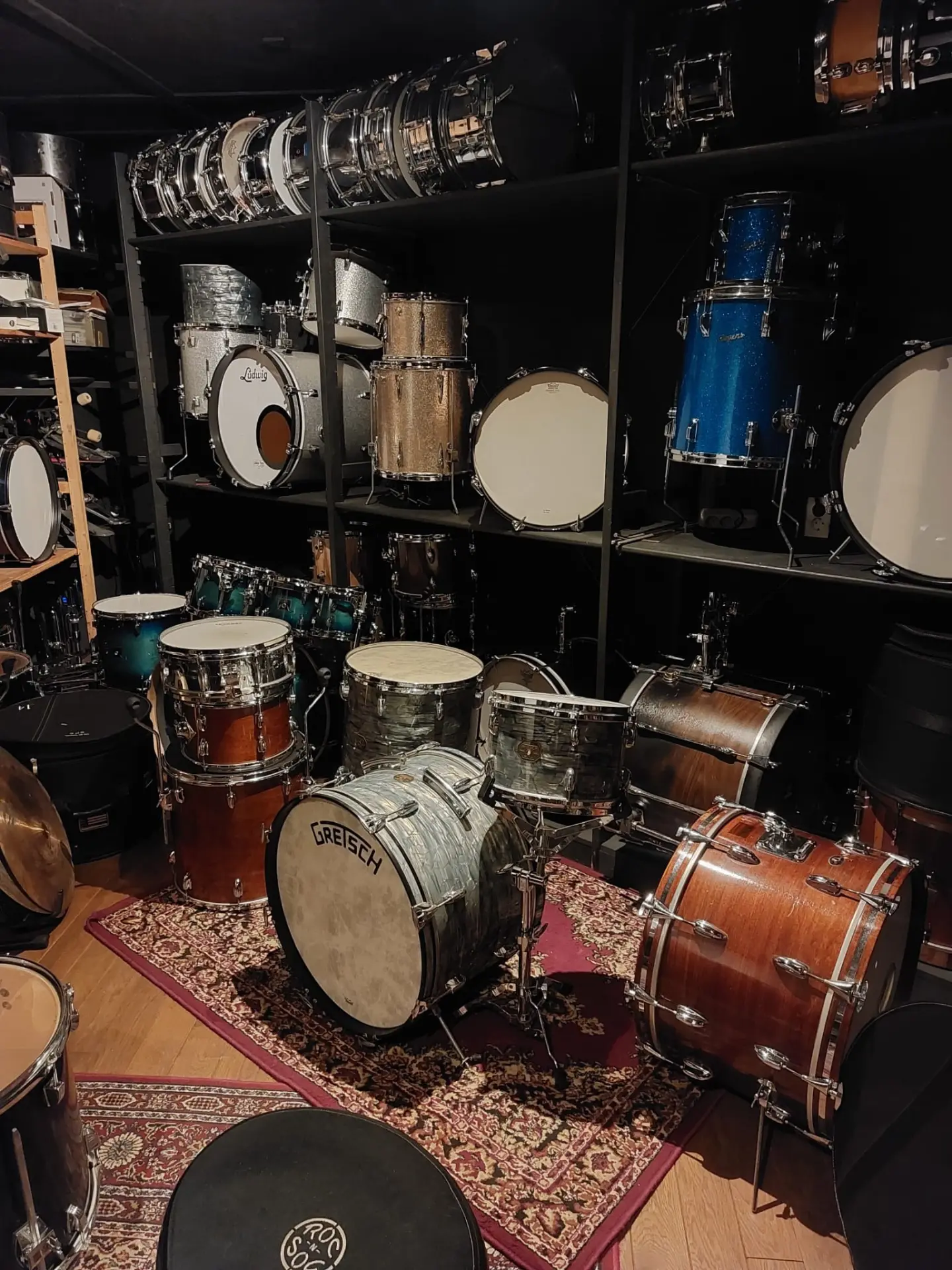 Drumcollectie van Drumhuis Helmond: drums op stellingen en een Gretsch drumstel op de vloer